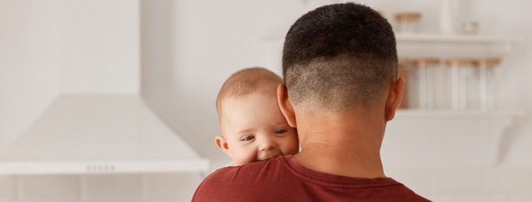 Homem de costas segurando um bebê