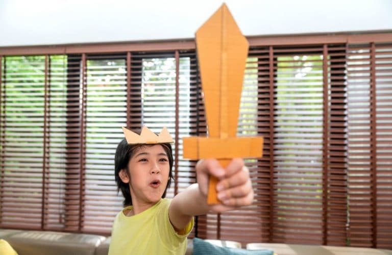 Criança brincando com espada de papelão