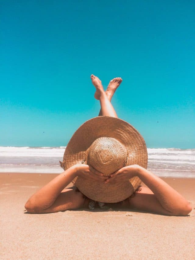 mulher de férias na praia deitada na areia