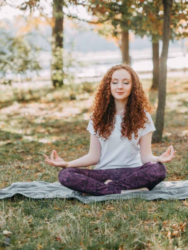 mulher sentada na grama em meditação