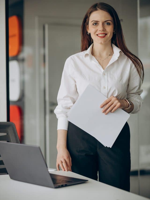 Business woman at office standing by a computer