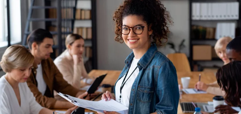 Mulher de óculos segurando papéis em uma reunião empresarial