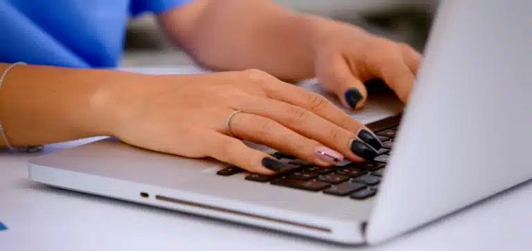 mão de mulher, branca, digitando em um teclado de notebook