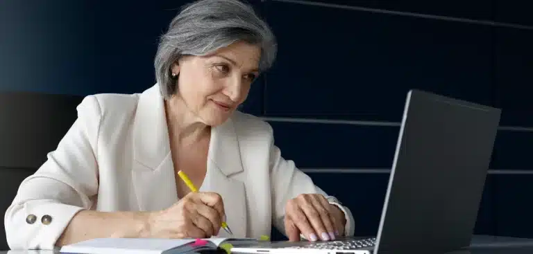 Mulher escrevendo e olhando a tela do notebook